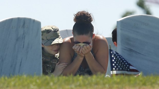 Heidi Hannah holds her head in her hands, as she is joined by her sons Tomas, 10, left, and Lucas, 8, right, at a Memorial Day visit to the grave of her oldest son, Army Specialist Taylor Hannah, at the Sacramento Valley National Cemetery in Dixon, California