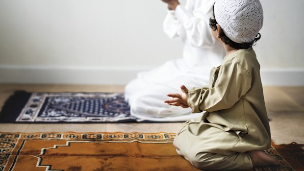 Little boy praying alongside his father during Ramadan Eid Muslim Islam