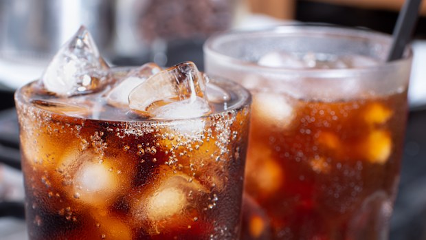 cola with crushed ice in glass and there is water droplets around. cool black fresh drink.