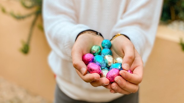 little girl holding chocolate easter eggs with her hands