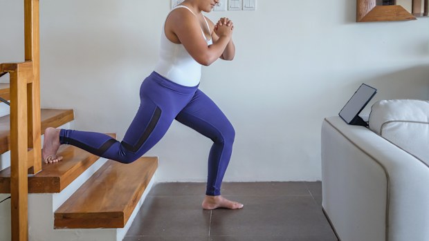 Portrait shot of an Asian woman doing lower body exercise in the stairs of her home