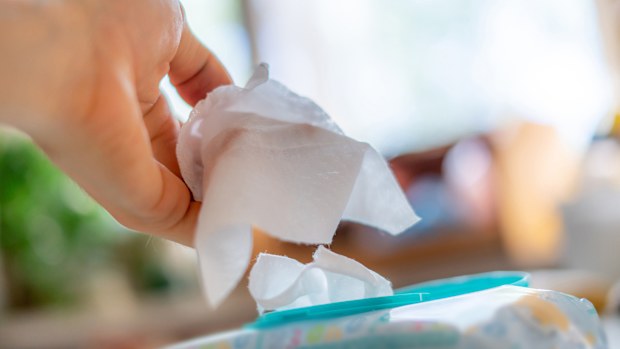 hand taking the wet wipe to clean skin