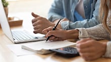 Close up spouses calculating family budget paying utility bills online using laptop, check loan payments, counting expenses. Economy, save money, finances management and planning, paperwork concept