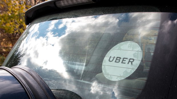 Rear window of a black Uber car with the white Uber sticker on the glass.