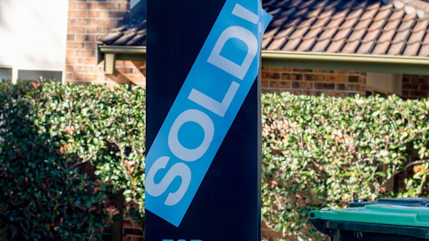 For sale sign near the residential building house with 'SOLD' sold sticker on it. Auction clearance rate