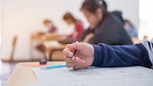 Exams test student in high school, university student holding pencil for testing exam writing answer sheet and exercise for taking in assessment paper on wood table classroom. Education study Concept