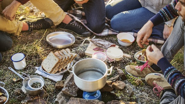Low section of friends preparing breakfast at campsite