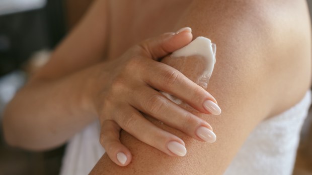 A person applying sunscreen to their arms.