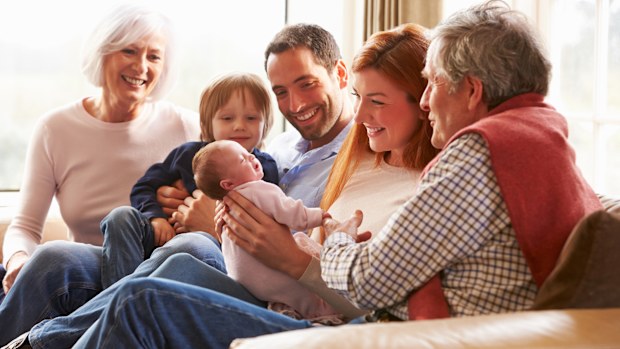 Grandparents, parents and children - including a new baby sitting on the couch together