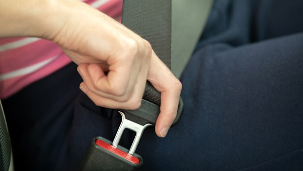 Close up of woman hand fastening seat belt while sitting inside a car for safety before driving on the road. Female driver driving secure and taking safe jorney.
