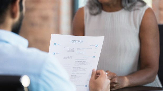 A businessman reads a resume during a job interview with a potential employee.