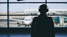 Passenger with headphones. Young man walking through airport terminal to airplane.