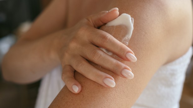A person applying sunscreen to their arms.