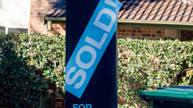 For sale sign near the residential building house with 'SOLD' sold sticker on it. Auction clearance rate