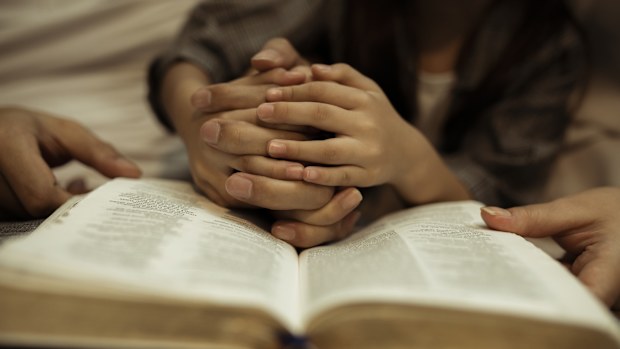 a kid reading the holy bible with guide by parents