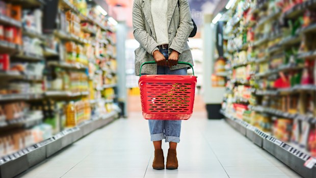 Supermarket aisle, woman legs and basket for shopping in grocery store. Customer, organic grocery shopping and healthy food on groceries sale shelf or eco friendly retail purchase in health shop