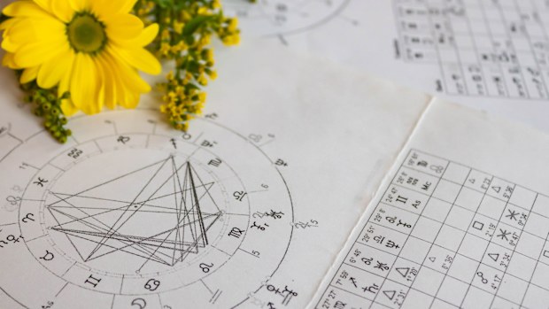 Printed astrology charts with yellow flowers in the background