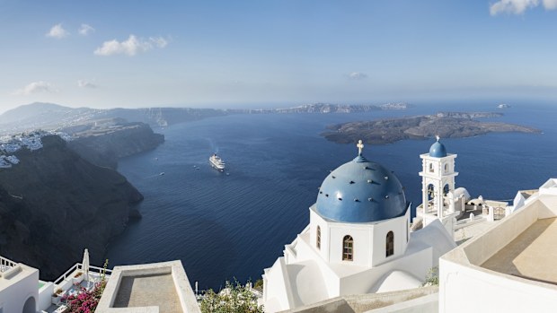 Early morning view in Santorini of the Imerovigli church sitting on top of the volcanic caldera. Santorini in Greece is one of the most famous travel destination in the World with numerous cruise ships anchoring in the bay below. The architecture is also famous for the duotone colors of the white painted buildings and light blue details.