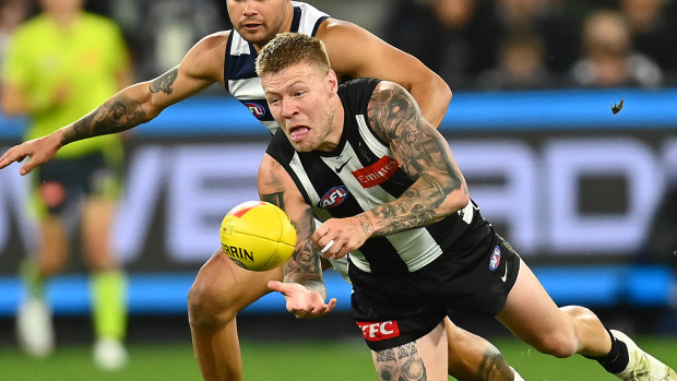 Collingwood's Jordan De Goey handballs whilst being tackled  by Geelong's Brandan Parfitt.