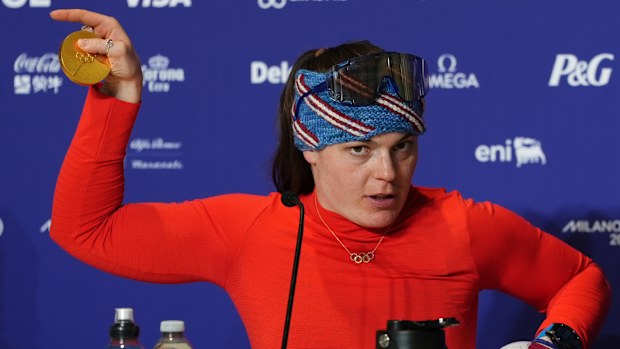 American gold medalist Breezy Johnson displays her broken medal to the media following her victory in the women's downhill.