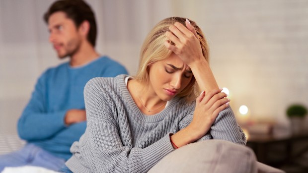 Relationship Crisis. Depressed, blonde wife sits next to indifferent husband who appears to be rolling his eyes. 