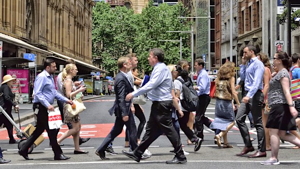 Sydney, Australia - November 12, 2015: People crowd crossing street in central Sydney. Landmark in background, shopping center to the left.