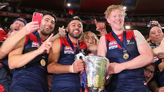 Christian Petracca, Christian Salem and Clayton Oliver of the Demons pose with the premiership cup.