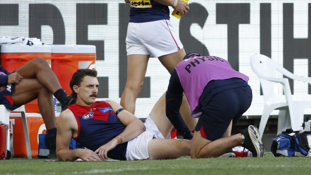 Jake Lever receives treatment after injuring his knee during the Demons' round-two match against the Hawks.