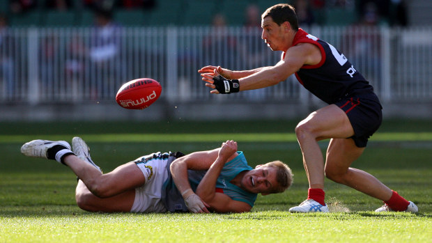 Melbourne s Nathan Brown steels a handball from Port's Kane Cornes.