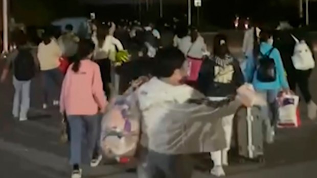  In this photo taken from video footage and released by Hangpai Xingyang, people with suitcases and bags are seen leaving from a Foxconn compound in Zhengzhou in central China's Henan Province in October 2022.