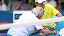 Alex de Minaur of Australia receives attention from a trainer.