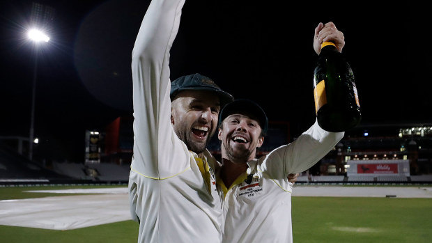 Nathan Lyon and Travis Head share a toast with a bottle of champagne out in the middle.