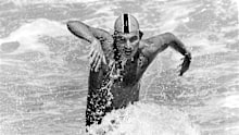 Former world champion John Holt churns up the foam as he dashes from the surf in the first leg of an Iron Man race.