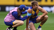 Brad Sheppard is attended to by a club trainer after a hit.