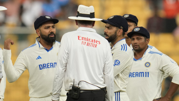 India's captain Rohit Sharma, center, speaks to the umpires after bad light stopped play on the day four of the first cricket test match between India and New Zealand at the M.Chinnaswamy Stadium, in Bengaluru, India, Saturday, Oct. 19, 2024. (AP Photo/Aijaz Rahi)