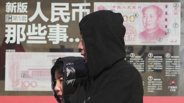 Residents walk past board highlighting the security markers on the latest Yuan note