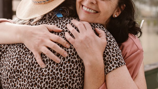 Two women hugging with a smile stock photo.