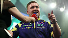 Luke Littler gestures to the fans