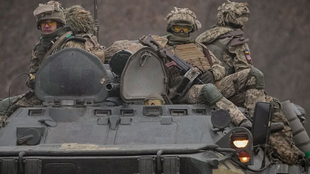 Ukrainian servicemen sit atop armored personnel carriers driving on a road in the Donetsk region, eastern Ukraine.