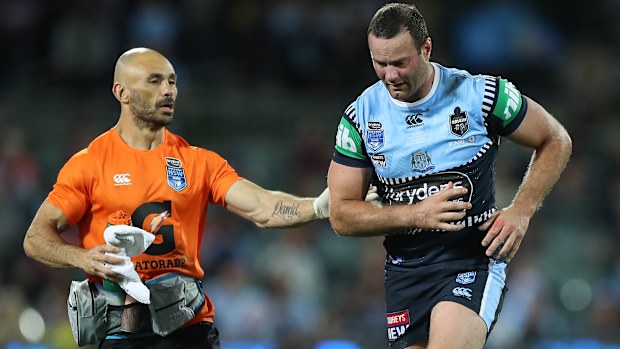 An unsteady Boyd Cordner is attended to by the NSW trainer.