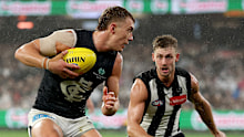 Patrick Cripps of the Blues evades a tackle by Harry Perryman of the Magpies.