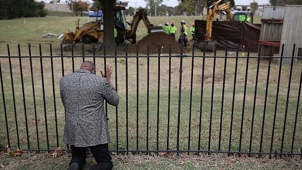 The Rev. Robert Turner prays as crews conduct a test excavation in October, 2020.
