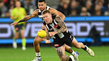 Collingwood's Jordan De Goey handballs whilst being tackled  by Geelong's Brandan Parfitt.