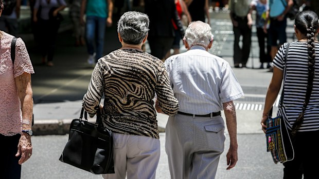 An elderly couple walks down the street in Brisbane.