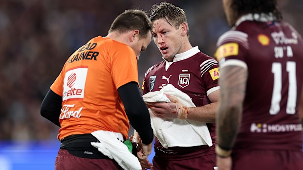 Harry Grant of the Maroons is attended to by a trainer after copping a knock to the face.
