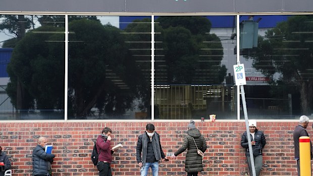 People are seen queuing outside a yet to open Centrelink office in Heidelberg, Melbourne, Tuesday, 