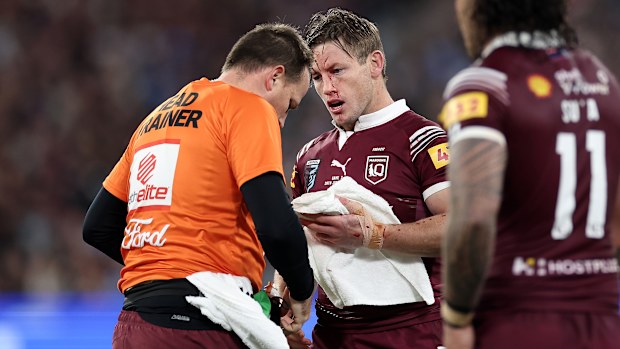 Harry Grant of the Maroons is attended to by a trainer after copping a knock to the face.