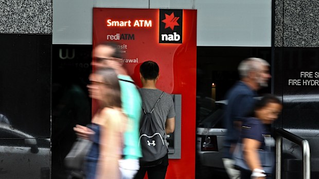 A man uses an NAB ATM as pedestrians walk past.