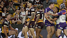 Will Warbrick of the Storm celebrates a try as Broncos players watch on.