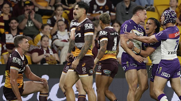 Will Warbrick of the Storm celebrates a try as Broncos players watch on.